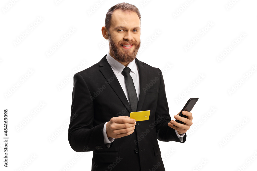 Businessman holding a credit card and a mobile phone and smiling at camera