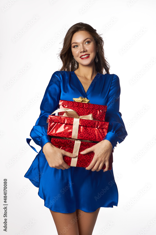 Beautiful young woman with gift in hands. Woman in a blue dress on a white background hold red gift boxes. Holiday shopping Beautiful young woman with gift in hands. Woman in a blue dress on a white background hold red gift boxes. Holiday shopping