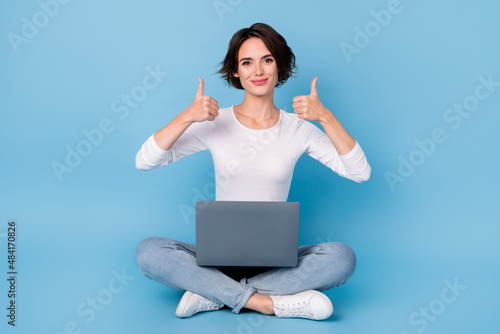 Photo of pretty cute lady dressed white shirt legs crossed holding modern device thumbs up isolated blue color background © deagreez