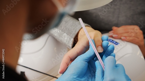 Nail care at home. Process of nail treatment in a nail salon. A view from behind the nail master shoulder of the nail care process.