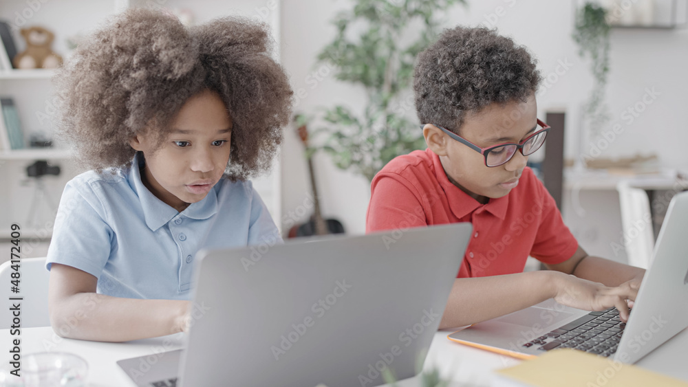 Boy and girl working on school assignments on laptops, distance education Boy and girl working on school assignments on laptops, distance education