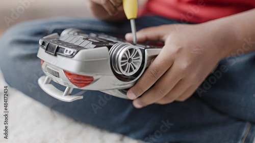 African American boy fixing broken toy car with screwdriver  learning new skills