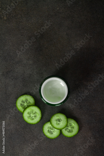 Green jar with cucumber cream on a black background
