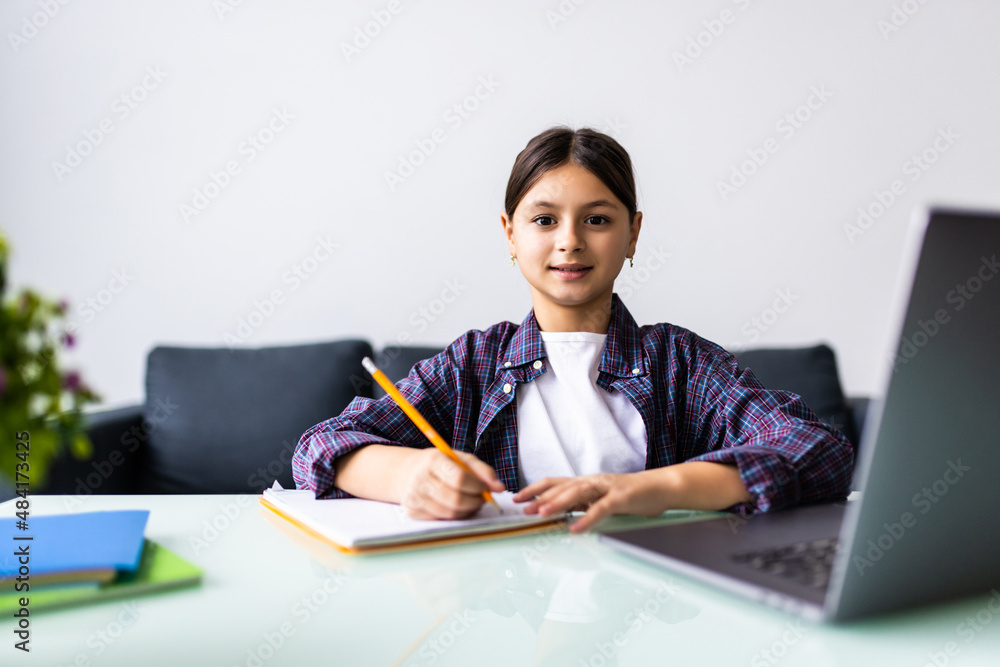 Young Little girl doing her homework at home and using a laptop Young Little girl doing her homework at home and using a laptop