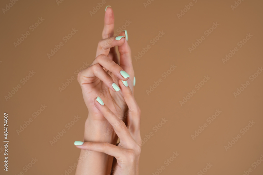 Graceful female hands with thin long fingers and mint turquoise manicure on a beige background Graceful female hands with thin long fingers and mint turquoise manicure on a beige background