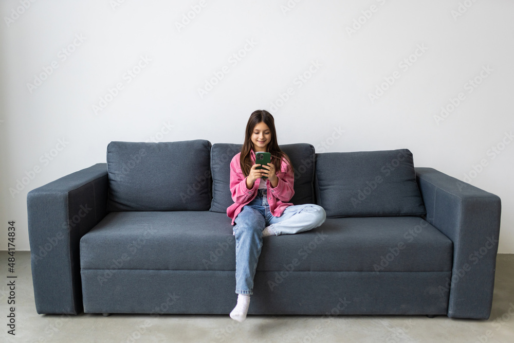 Positive school girl study remote rest relax use smartphone quarantine stay home information sit comfort couch Positive school girl study remote rest relax use smartphone quarantine stay home information sit comfort couch