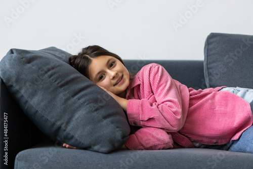 Beautiful school teen girl smile while lying on a sofa in the living room