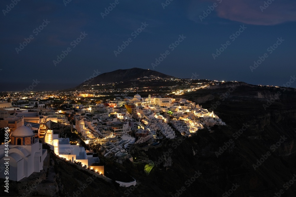 Panoramic view of the picturesque illuminated village of Fira Santorini Greece at night time