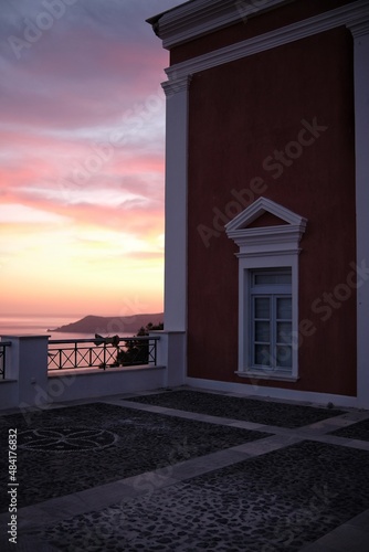 View of a traditional residential building and a beautiful pink sunset in the background in Santorini Greece