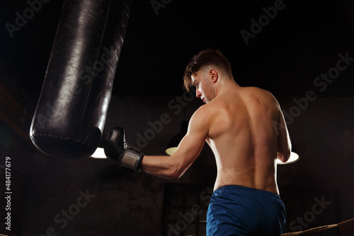 A boxer trains in the gym strikes a punching bag.