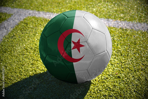 football ball with the national flag of algeria lies on the green field
