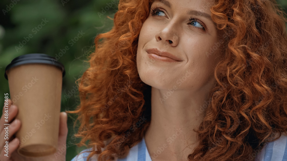 dreamy redhead woman holding paper cup outside. dreamy redhead woman holding paper cup outside.