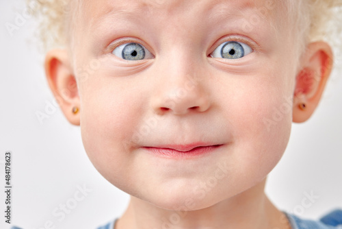 child beautiful girl with wide eyes  look at camera in surprise. Children s products   clothing and accessories. Expressive facial emotions. blonde kid with blue eyes  close-up portrait