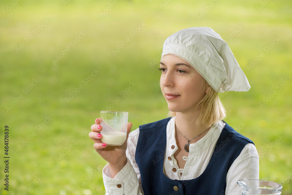 Latvian woman in traditional clothing with milk glass on nature Latvian woman in traditional clothing with milk glass on nature