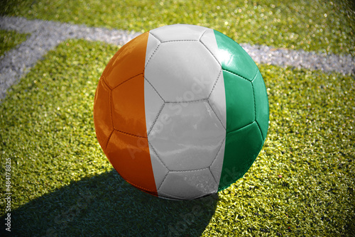 football ball with the national flag of cote divoire lies on the green field