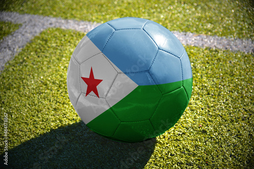 football ball with the national flag of djibouti lies on the green field