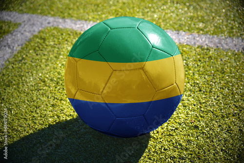 football ball with the national flag of gabon lies on the green field