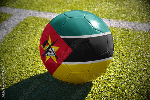football ball with the national flag of mozambique lies on the green field
