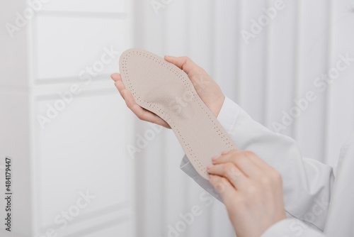 Doctor holding orthopedic insoles in his hands. Orthopedist tests the medical device. Orthopedic insoles on a white. Foot care. Flat Feet Correction. Prevention of flat feet and foot diseases