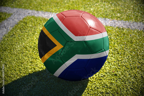 football ball with the national flag of south africa lies on the green field