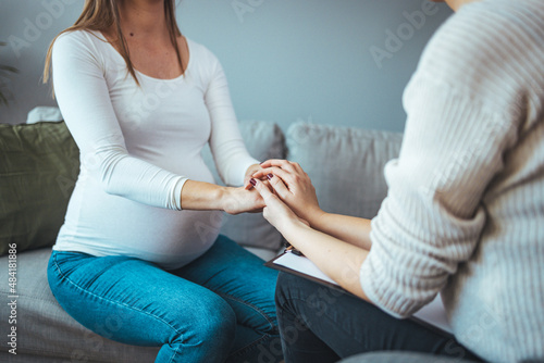 Fototapeta Naklejka Na Ścianę i Meble -  Pregnant support group meetup in a house. Supporting patient. Psychologist hold hands of girl patient, close up. Abortion decision. Psychological therapy, survive personal crisis