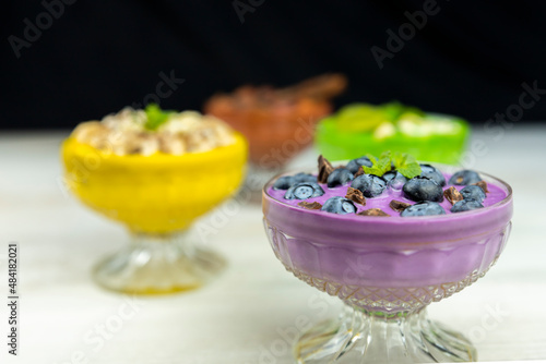 Smoothie or pudding with blueberries and chocolate served in a bowl for breakfast with several other smoothies in background photo