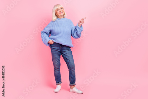 Full length body size view of attractive cheerful grey-haired woman demonstrating copy space ad isolated over pink pastel color background