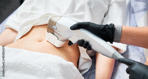Slika na platnu Close up doctor cosmetologist using ultrasound device while performing lifting procedure on woman abdomen