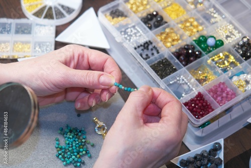 Female designer making jewelry at workplace. Selective focus.