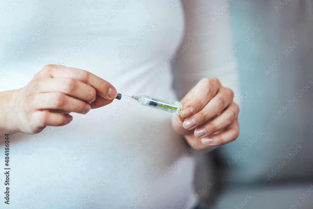 Pregnant woman injects anticoagulants into her stomach, isolated on