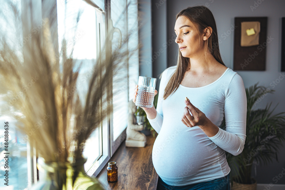 Picture of pregnant woman taking medication pills. Pregnant woman