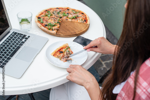 Top view of business woman eating pizza while working at a pizza restaurant