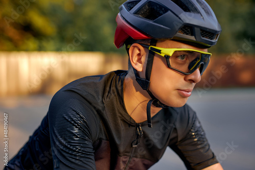 Young caucasian cyclist in black helmet, protective glasses and active wear dynamically riding bicycle. Man preparing for competitions and races on fresh air. outdoors in nature, on road © alfa27
