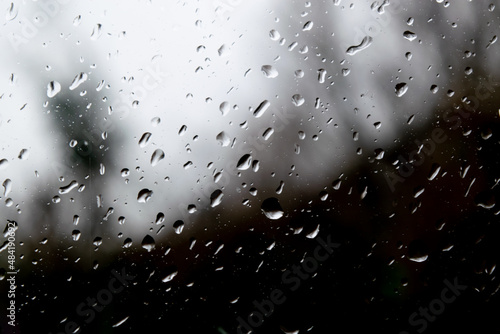 Raining dropping on the glass door window, bubble transparent outside black and white background. Focus foreground 