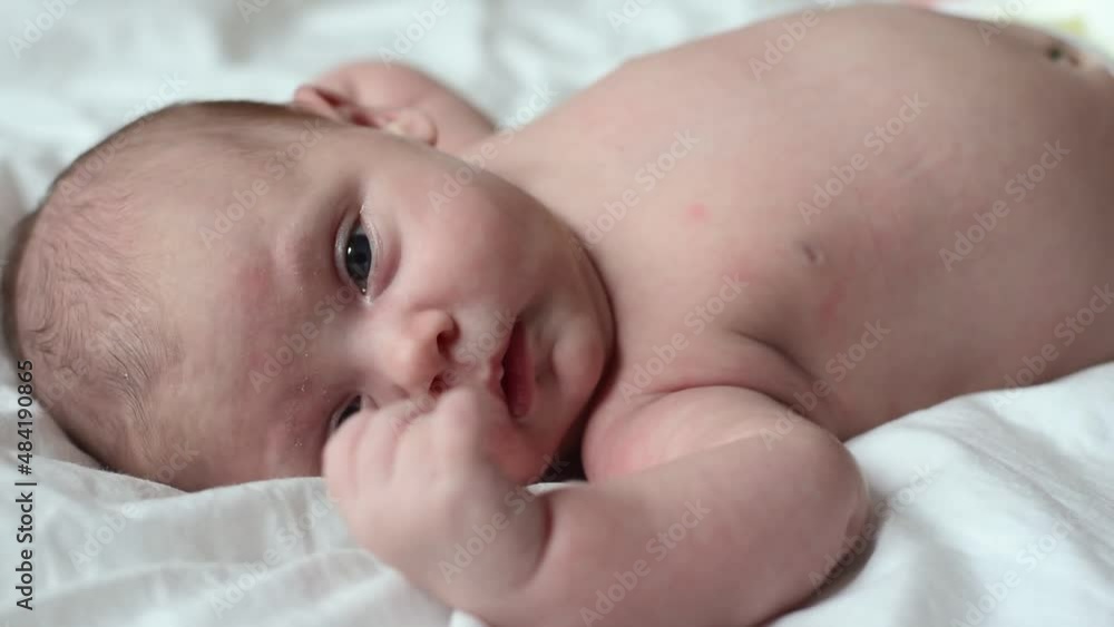Closeup portrait of Newborn baby on white blanket. Soft focus. Infant is lying on her side. One, two week age. Infant girl waking up on bed at home. New life and growing up concept. Real People. Closeup portrait of Newborn baby on white blanket. Soft focus. Infant is lying on her side. One, two week age. Infant girl waking up on bed at home. New life and growing up concept. Real People.