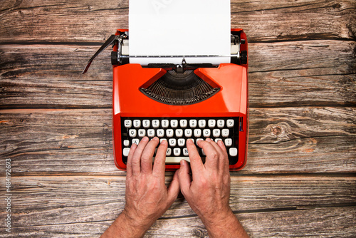 Manos de hombre escribiendo en una máquina de escribir sobre una mesa de madera rústica. Vista superior. Copy space