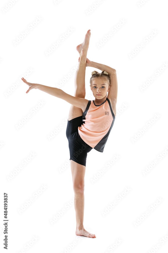 Little flexible girl, rhythmic gymnastics artist isolated on white studio background. Grace in motion, action. Doing exercises in flexibility.