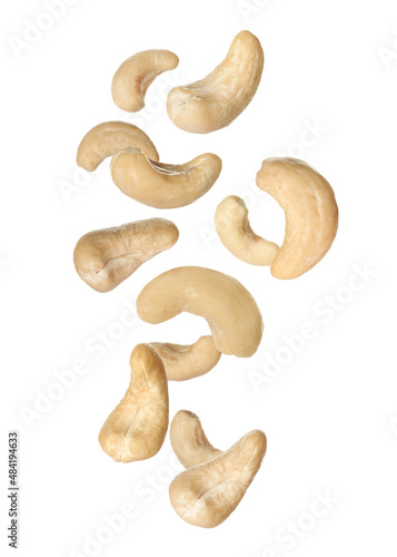 Tasty raw cashew nuts falling on white background