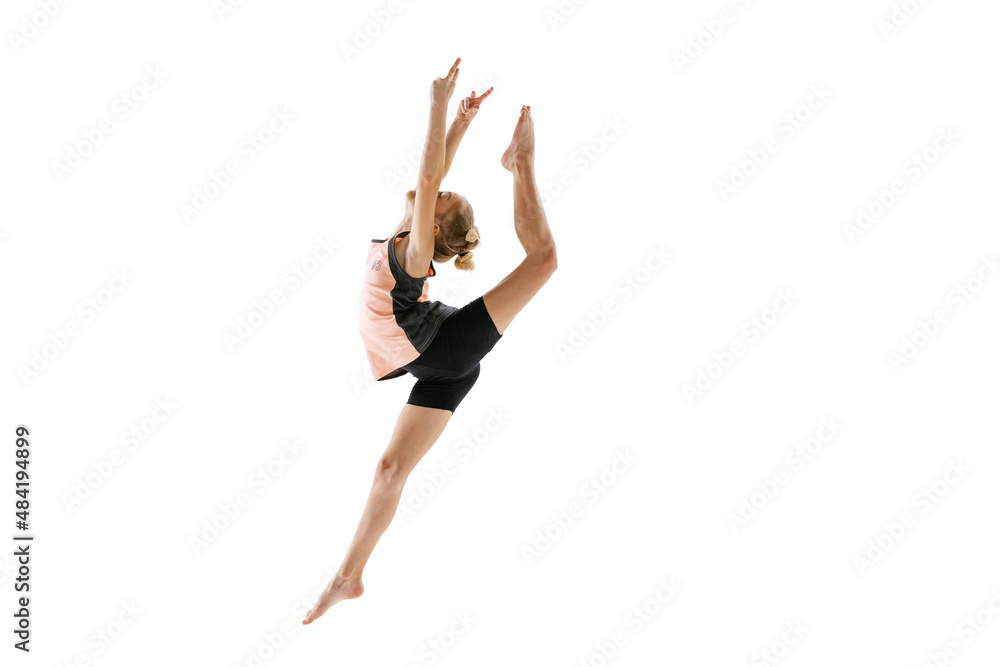 Little flexible girl, rhythmic gymnastics artist jumping isolated on white studio background. Grace in motion, action. Doing exercises in flexibility.
