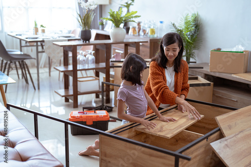 mother and daughter assembling new furniture together