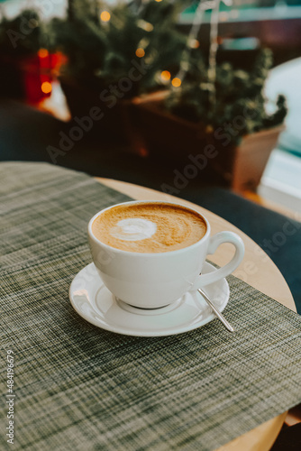 A large white cup with hot cappuccino on vegetable milk on the table. Coffee on almond milk with beautiful latte art in a coffee shop