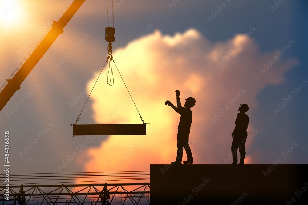 Fototapeta premium Silhouette of Engineer and worker on building construction site at sunset in evening time.