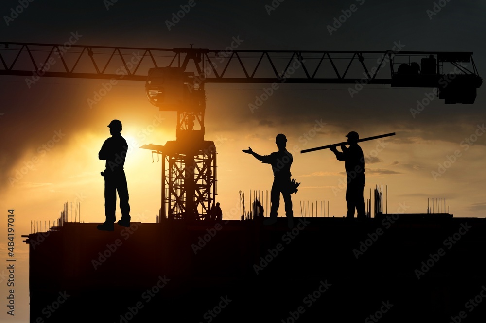 Fototapeta premium Silhouette of Engineer and worker on building construction site at sunset in evening time.