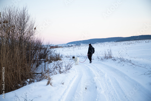 man and his happy white dog enjoying winter snow outdoors on sunny day