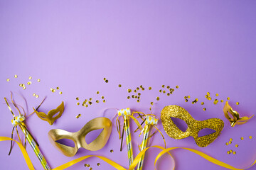 Flat lay composition for carnival or mardi gras background with golden carnival masks on violet background. Top view