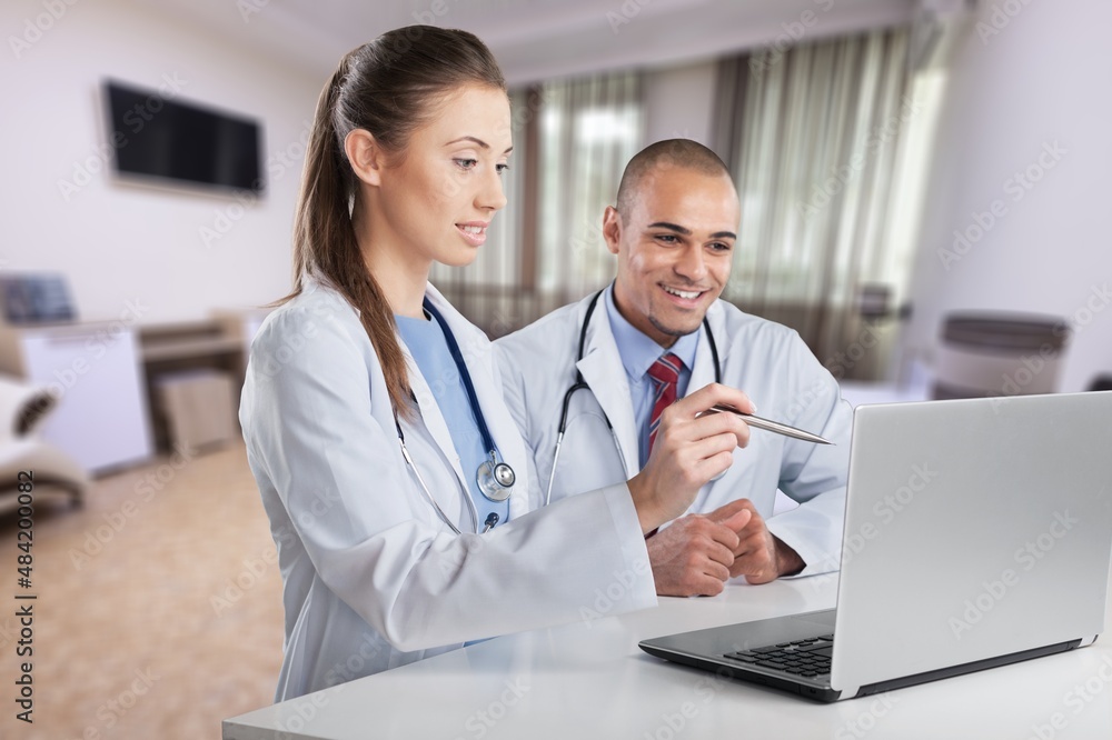 Thoughtful serious doctor physician sitting at work desk in office with laptop, Thoughtful serious doctor physician sitting at work desk in office with laptop,