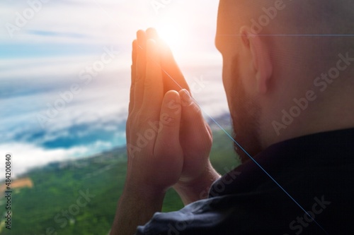 Human praying on the holy bible in a field during beautiful sunset.