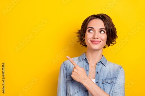 Photo of young lovely woman look indicate finger empty space promo ads banner isolated over yellow color background