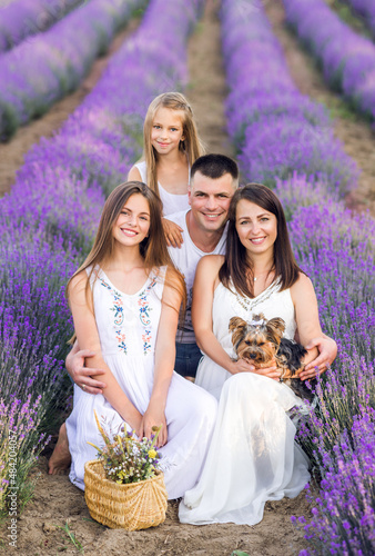 beautiful family and their little dog in a lavender field. Summer photo in purple colors.