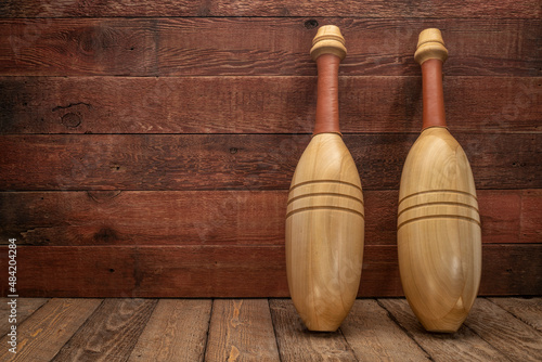 pair of wooden Indian clubs against rustic, weathered wood background - home gym and functional fitness concept photo